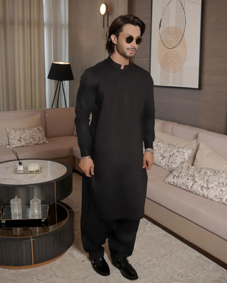 Man styled in a plain black Shalwar Kameez